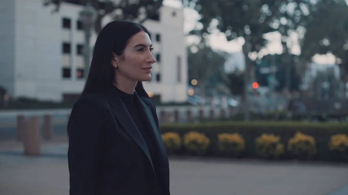 Natalie Weatherford attorney profile thumbnail. Shot in profile at dusk, a woman in a dark blazer with a white building behind her.