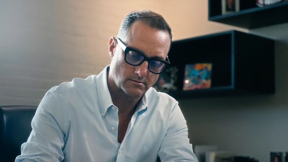 Ryan Cunningham attorney profile thumbnail. A man in a light blue shirt and dark-rimmed glasses sits at a desk looking down.