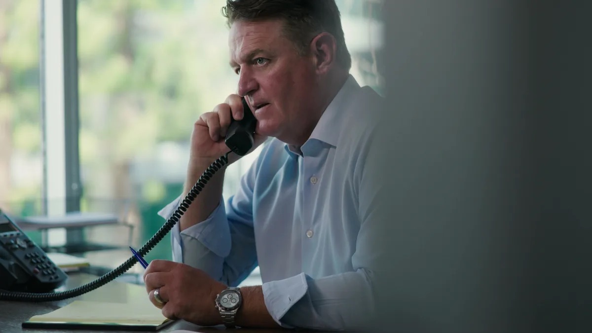 KMD Law FAQ video thumbnail on discretion. An attorney at his desk on the phone, sleeves rolled up, pen in hand, a window with green plants behind him.